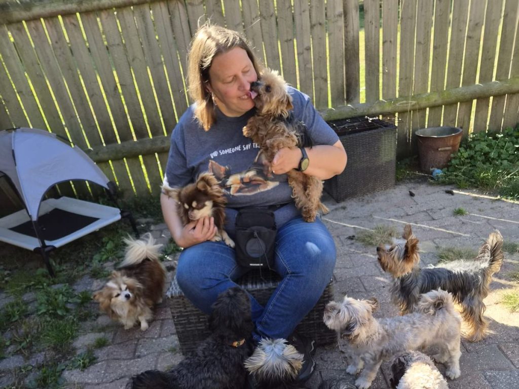 Sandra houdt een van de honden vast, met meer honden om haar heen